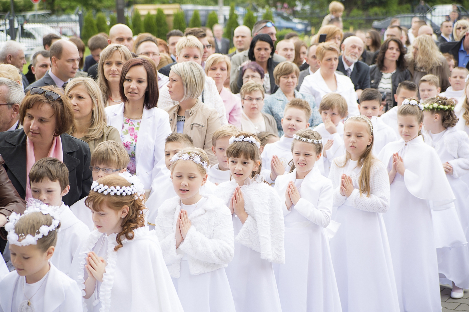 W trakcie sesji fotograficznej dziecko wraz ze swoimi rodzicami pozują na tle fotograficznym rozbawiając dziecko zabawkami